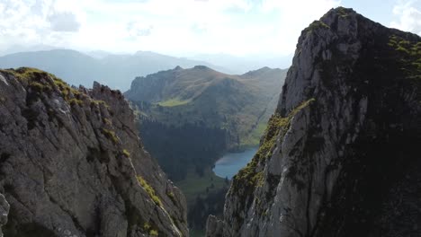 Volando-Con-El-Dron-Entre-Dos-Rocas-A-Un-Hermoso-Lago-De-Montaña-Suizo