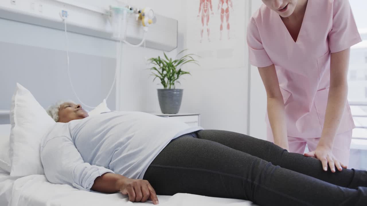 fisioterapeuta feliz y diversa tratando la pierna de una paciente anciana, cámara lenta