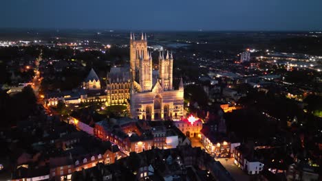 Aerial-drone-video-displays-the-famous-Lincoln-Cathedral-in-Lincolnshire,-UK,-at-dusk,-showcasing-its-illuminated-Gothic-architecture