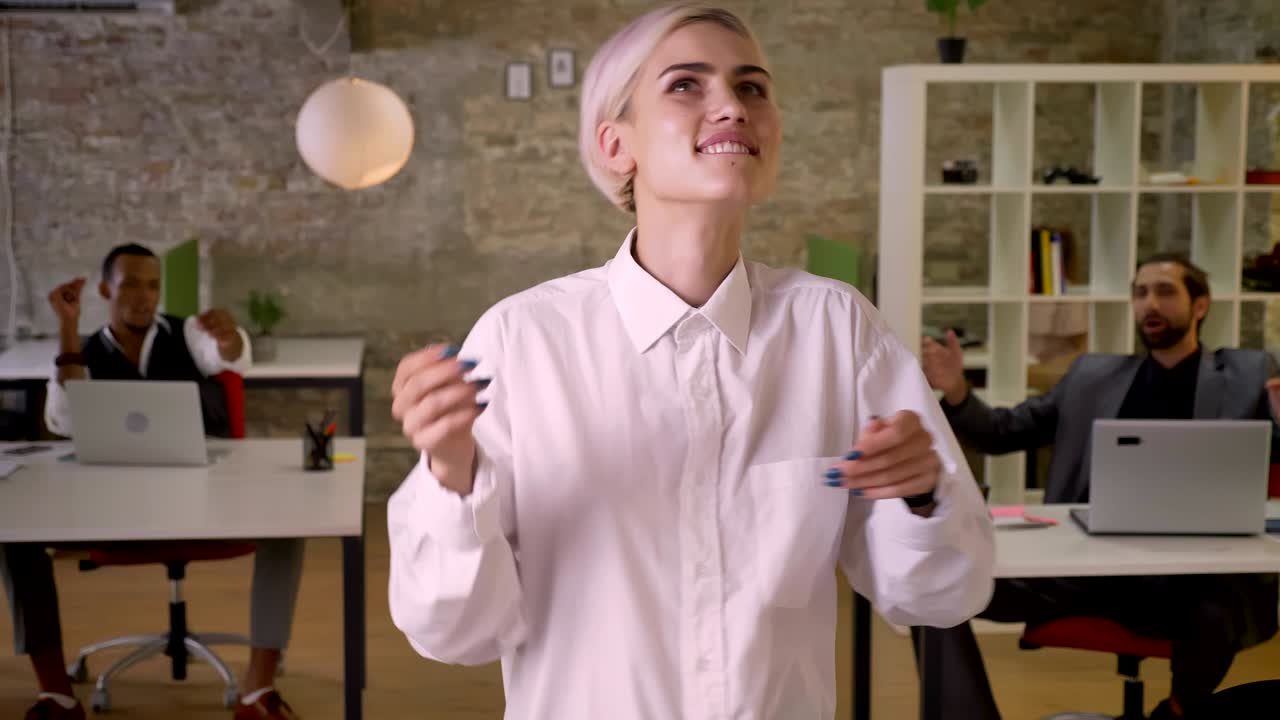 Young happy businesswoman is dancing in office, colleagues are clapping, work concept, relax concept
