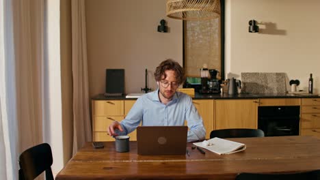 hombre trabajando desde casa en una computadora portátil en la cocina