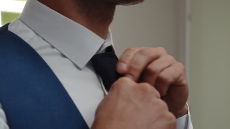 groom's preparing his tie close up