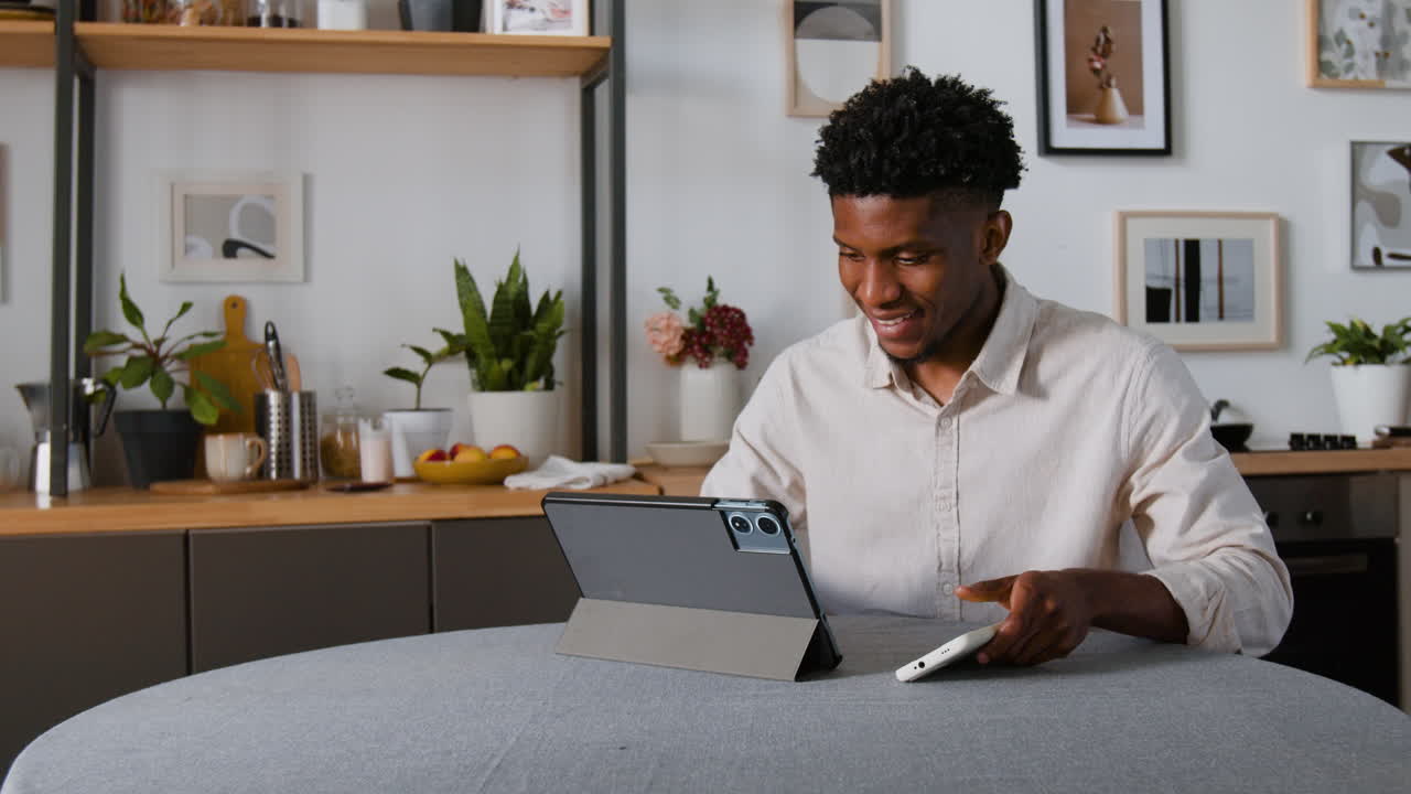 Man using tablet and phone in kitchen