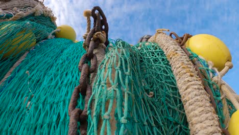 upward view of green fishing net with chains and yellow buoys