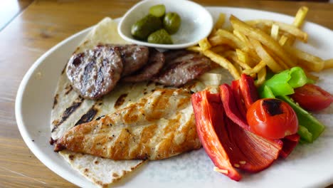 pollo a la parrilla con albóndigas, papas fritas y verduras