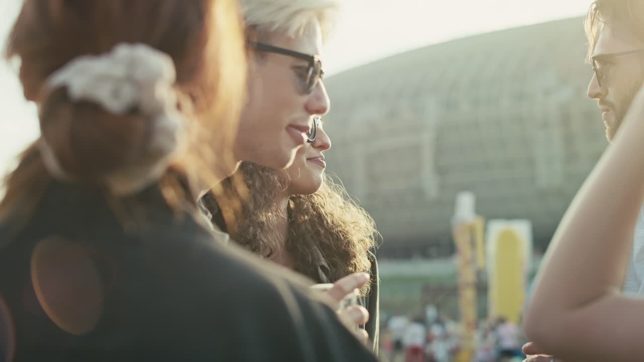 Gruppe af unge kaukasiske venner snakker og hygger sig på en musikfestival.