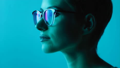profile portrait of a woman in glasses under blue light