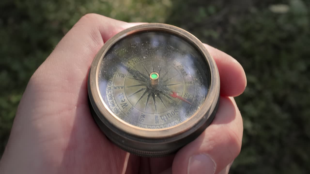 여행자의 손은 여름의 숲에서 오래된 방향성 나침반을 들고 있으며, 사람은 위치를 찾기 위해 나침반으로 이동합니다.