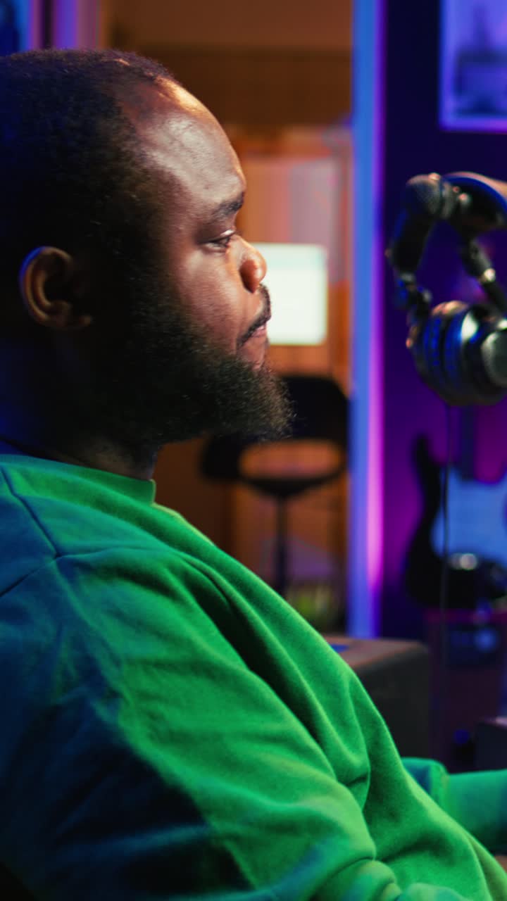 Uomo afroamericano che lavora in uno studio creativo domestico con luci al neon