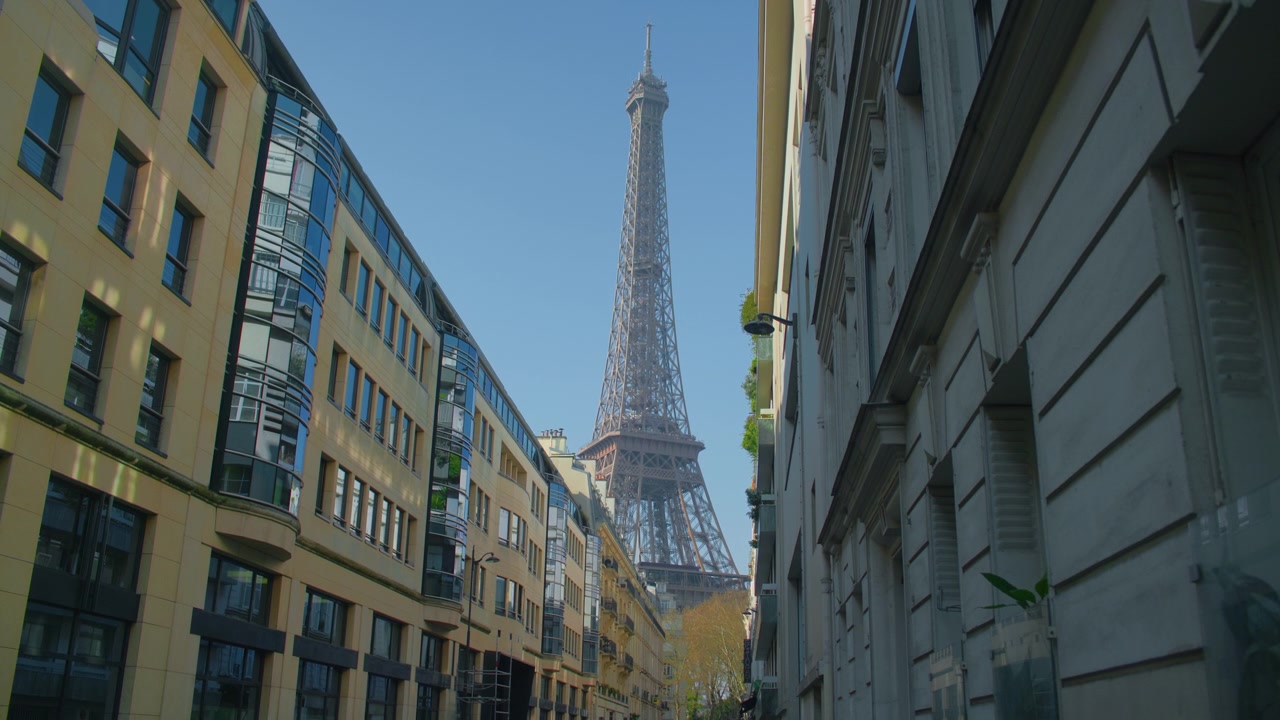 Torre Eiffel, Parigi, con edifici di vicoli e cielo blu sullo sfondo, ripresa a mano libera. Vista panoramica del simbolo della capitale francese incorniciato dall'architettura tradizionale parigina