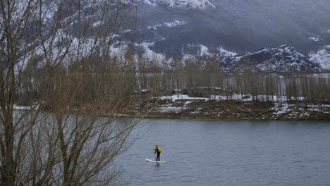 Man-on-paddle-board-between-water-and-mountains-on-coast