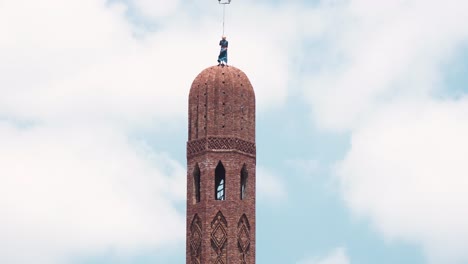 mid shot for the man on the top of the minaret finish it without any ppe