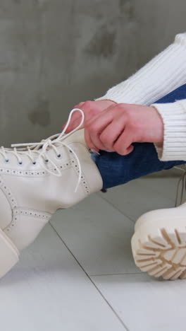 woman putting on cream-colored lace-up boots