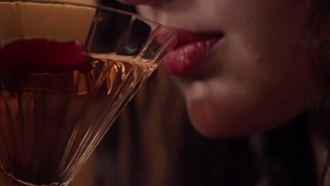 a pretty young woman drinks a martini.