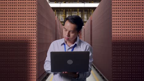 asian male professional worker standing with his laptop with red brick packed in stacks are stored, he is nodding his head with dissapionted