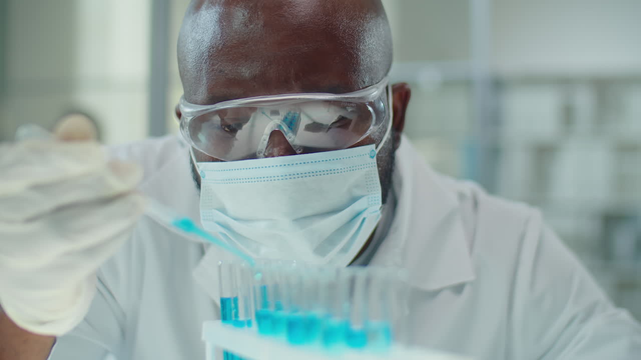 African American Lab Worker in Mask Pouring Blue Chemical in Test Tubes