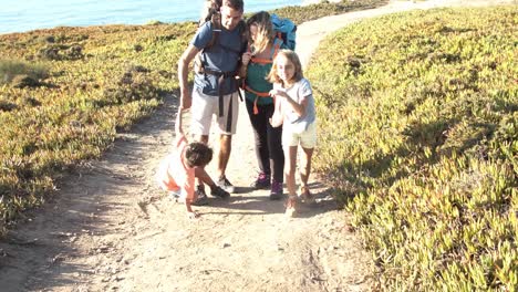 active parents with backpacks and kids walking on path at sea