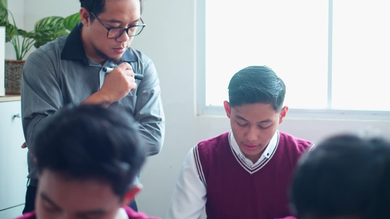 Male Teacher Observes Students Diligently Or Supervising students who are taking exams In Classroom