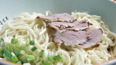 close up of typical chengdu food- mi xian noodle with braised pork slices and spring onion, china