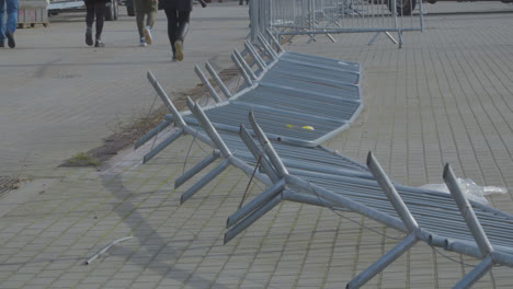 overturned metal safety barriers after strong hurricane - a group of people walk beside them