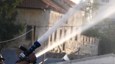 trabajo en equipo de bomberos, dos bomberos sosteniendo mangueras de agua, dirigiendo el agua al fuego