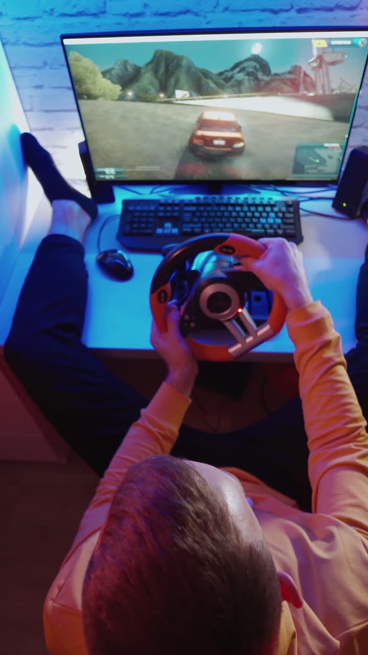 Uomo che gioca a un videogioco sul computer. Vista dall'alto di un gamer che usa un volante da gaming e gioca a un simulatore di guida automobilistica.