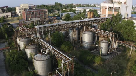 aerial shot of rusty factory containers and pipelines in abandoned industrial area