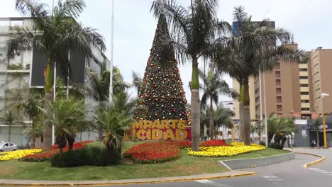 Weihnachtsbaum-Mitten-In-Einem-Kreisverkehr,-Umgeben-Von-Palmen-Und-Blumenarrangements