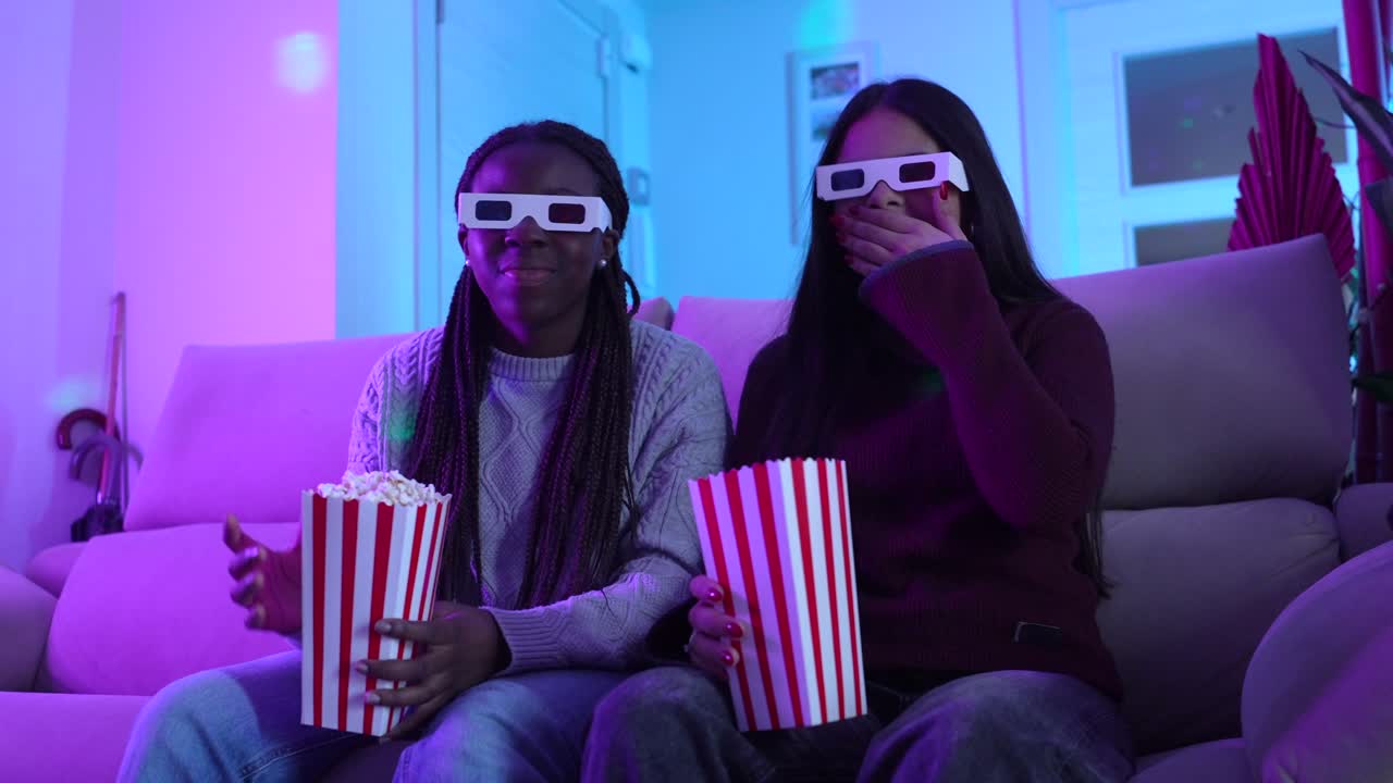 Two friends enjoying a movie night with 3D glasses and popcorn