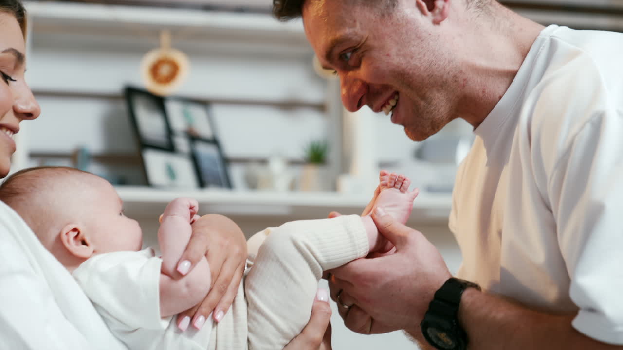 Happy smiling couple holding their newborn. Father is kissing tiny baby feet. Close up.