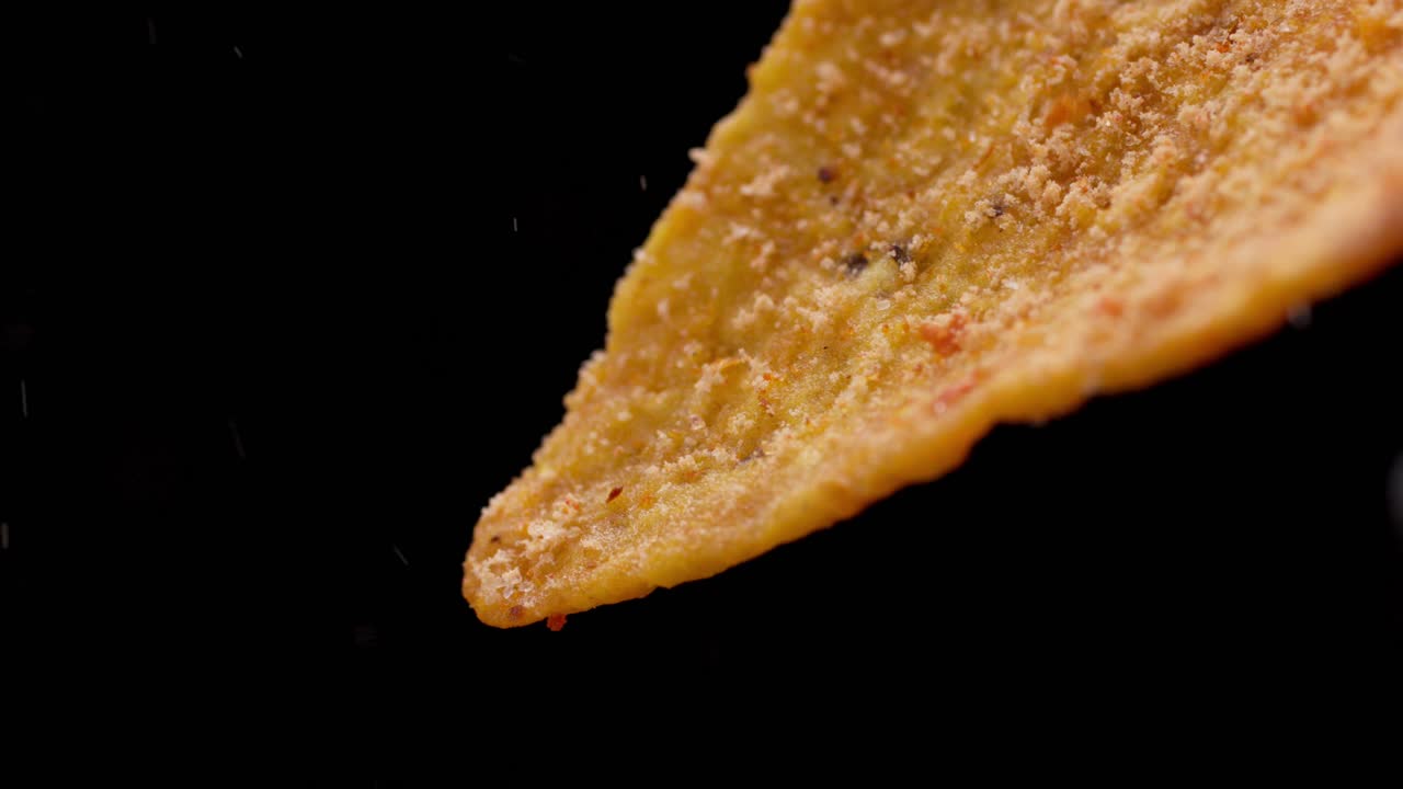 Pouring spicy chili powder on a dorito. Macro close up
