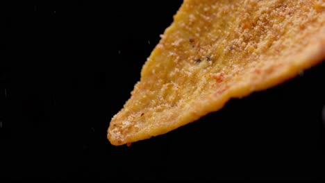 pouring spicy chili powder on a dorito. macro close up