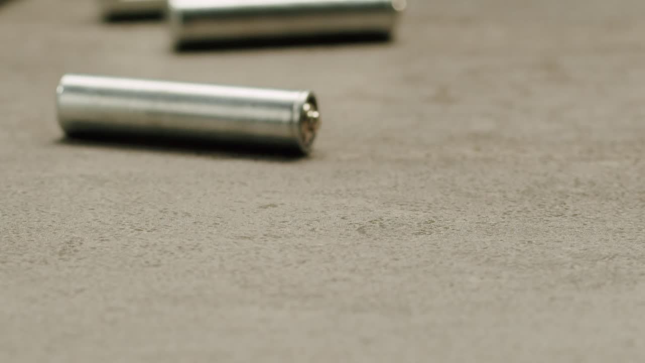 Silver batteries AA and AAA on black background close-up. Double-A battery is a standard size single cell cylindrical dry battery. Batteries are common in portable electronic devices. An AA battery is composed of a single electrochemical cell that may be either a primary battery or a rechargeable ba