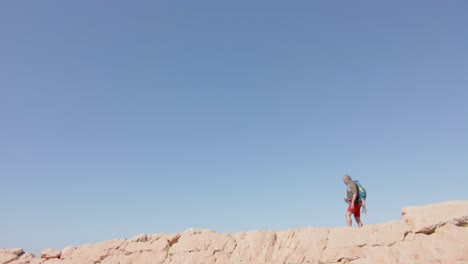 senior biracial man in mountains hiking, in slow motion