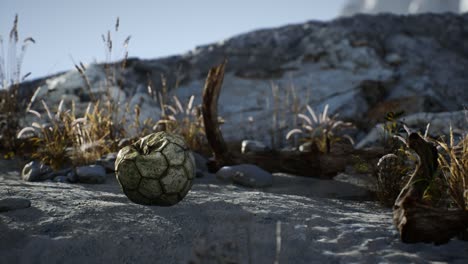 una vieja pelota de fútbol rota arrojada yace en la arena de la playa del mar