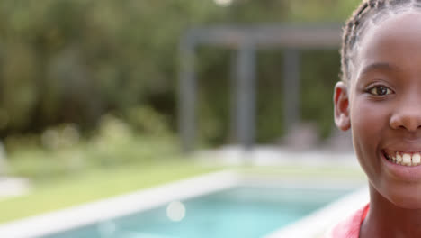 portrait of happy african american girl smiling by pool, copy space, in slow motion