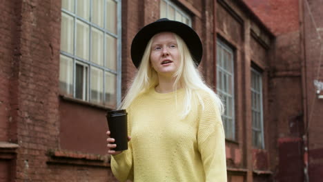 Woman-with-black-hat-holding-coffee-cup-outdoors