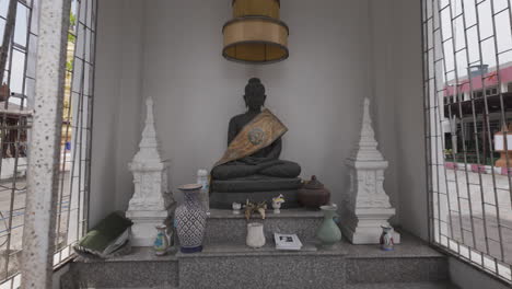 buddhist shrine with seated buddha statue in golden sash. wat muen ngoen kong in chiang mai, thailand. dolly-in shot