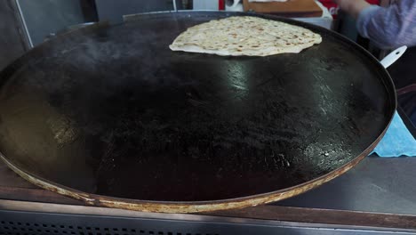 cocinando pan plano turco en una sartén grande