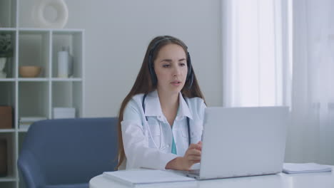 el médico usa auriculares, consulta a la paciente, hace una videollamada en línea con cámara web en la pantalla de la computadora portátil, videoconferencia de telemedicina, reunión virtual con aplicación de computadora remota.