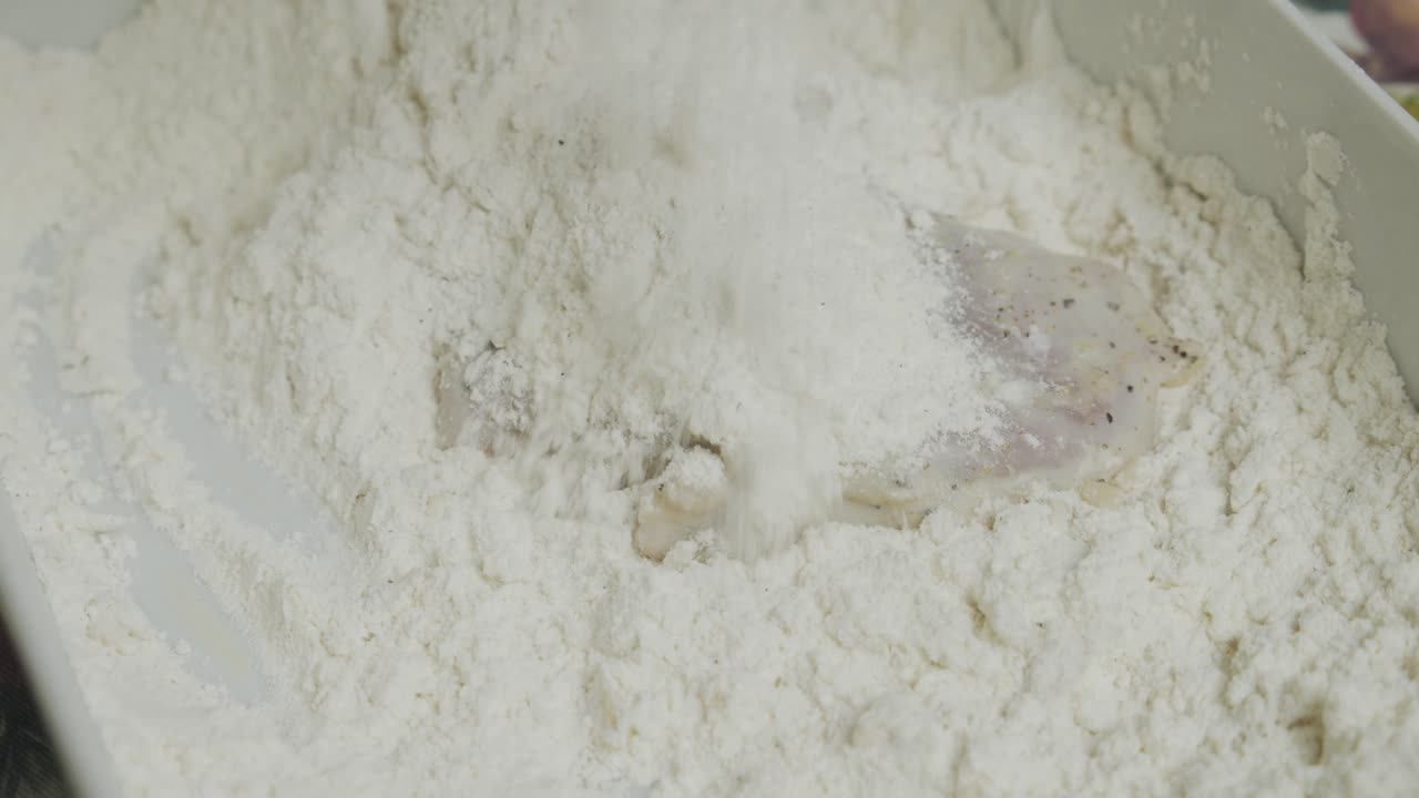 작은 세라믹 접시 안에 요리용 밀가루에 닭고기를 섞는다