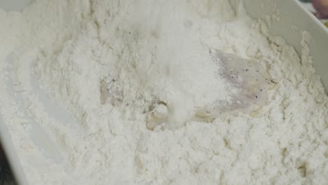 mixing chicken meat in cooking flour inside small ceramic plate