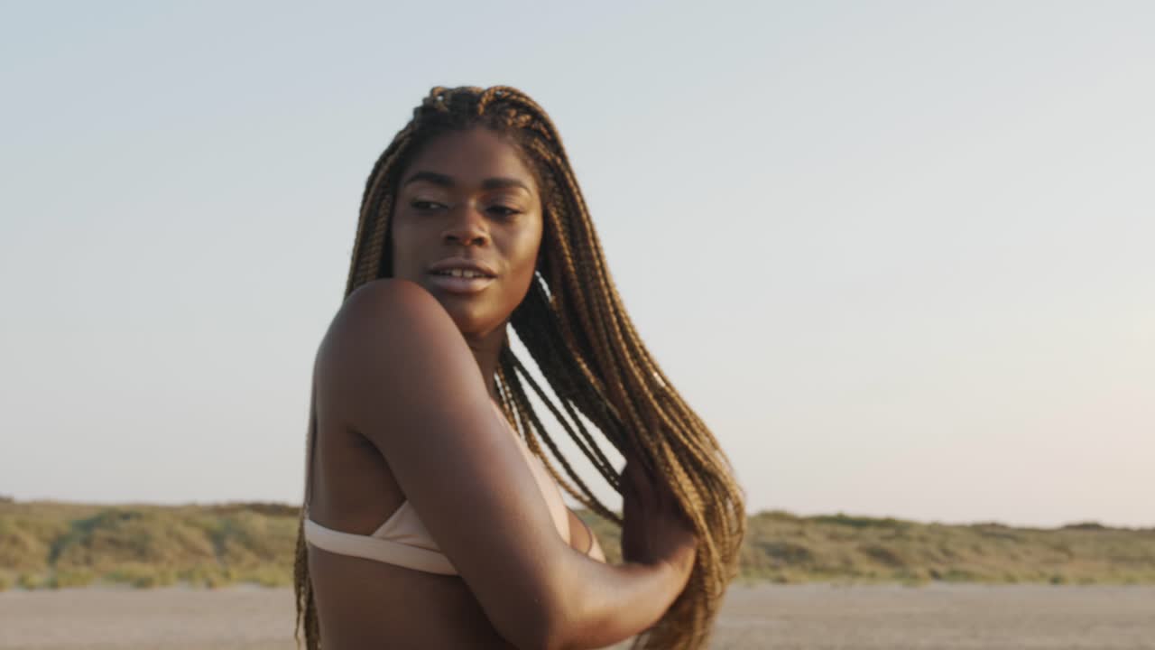 hermoso modelo negro posando en la playa con un conjunto de bikini