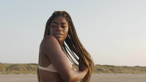 hermoso modelo negro posando en la playa con un conjunto de bikini