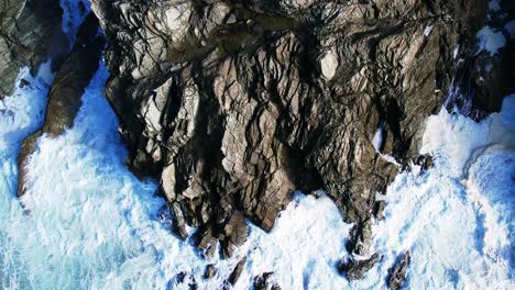 Rocas-Costeras-De-Cornualles-Con-Olas-Blancas-Arremolinadas-Del-Océano-Salpicando-Desde-Un-Dron-Aéreo-Disparado-Desde-Arriba