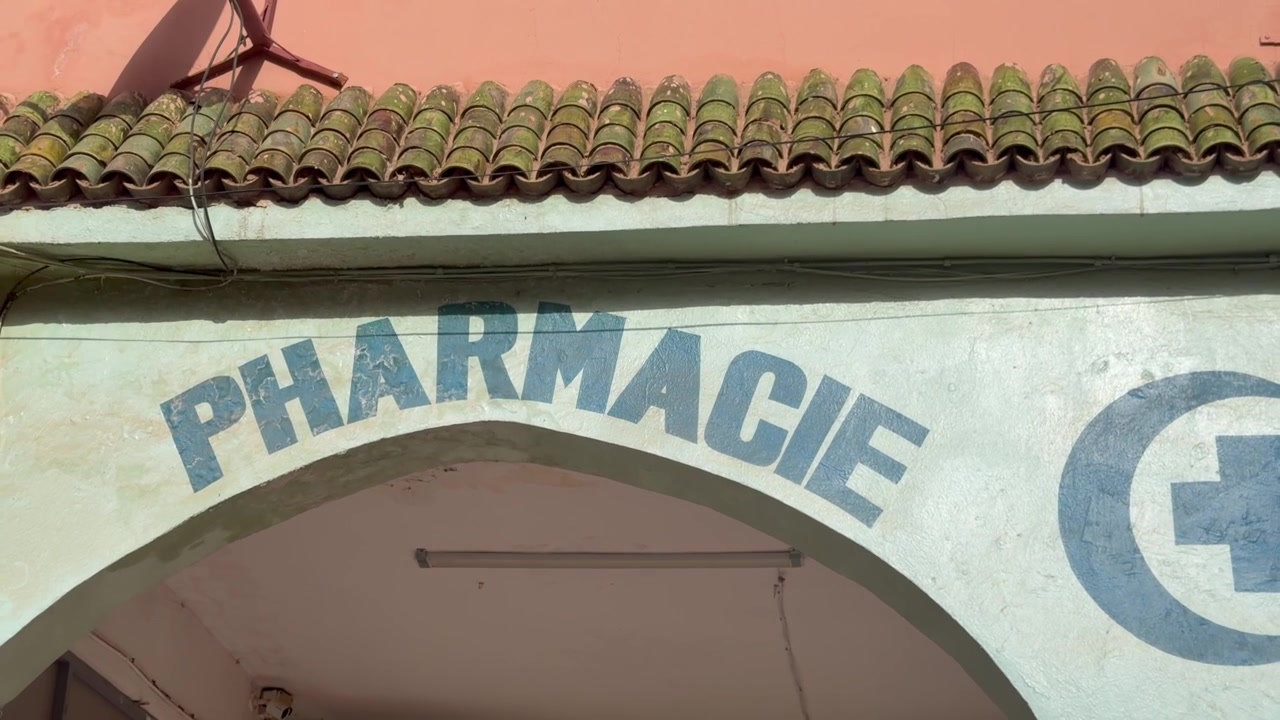 Vista ravvicinata dell'insegna d'ingresso di una farmacia su facciata ad arco con tetto in tegole, Marocco