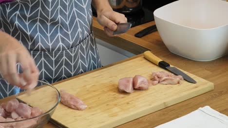 mujer cortando pollo para cocinar