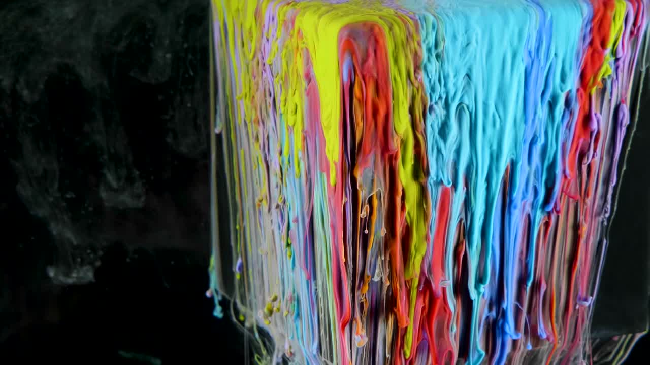 pintura de tinta multicolor fluye lentamente desde el cubo bajo el agua