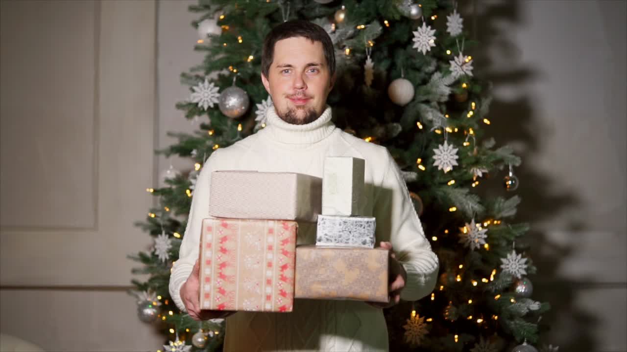 Man holding Christmas presents near a decorated Christmas tree