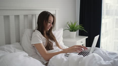 woman working on laptop in bed